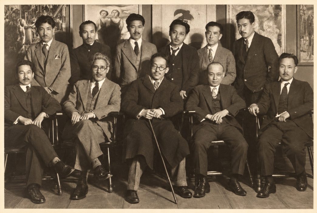 Participating artists in the first New York Shinpo-sponsored Japanese Artists Exhibition, New York, February 1927. Yasuo Kuniyoshi is seated at center in the front row, with Seimatsu Hamaji to his left; Eitaro Ishigaki is in the second row, between Kuniyoshi and Hamaji. Jisaburo Sugimori (also known as George Tera), standing in the back row, second from left, was identified by his granddaughter, Nancy Kitchen. On the wall at left is Bumpei Usui’s Furniture Factory (originally exhibited as The Carpenter’s Shop), with Yasuo Kuniyoshi’s Two Women beside it. Photograph courtesy of Nancy Kitchen and the Sugimori family.